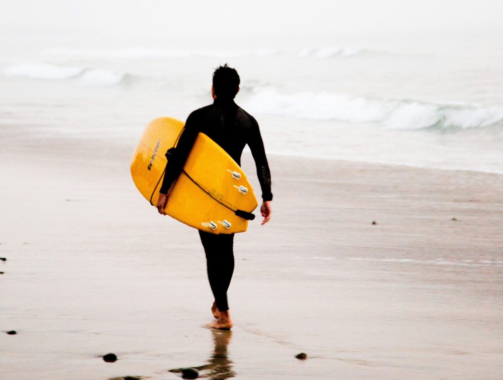 Surfers and families enjoying Hermosa Beach at sunset in South Bay